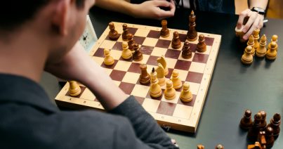 Pensive teenager play chess during chess competition in chess club. Education, chess and mind games.